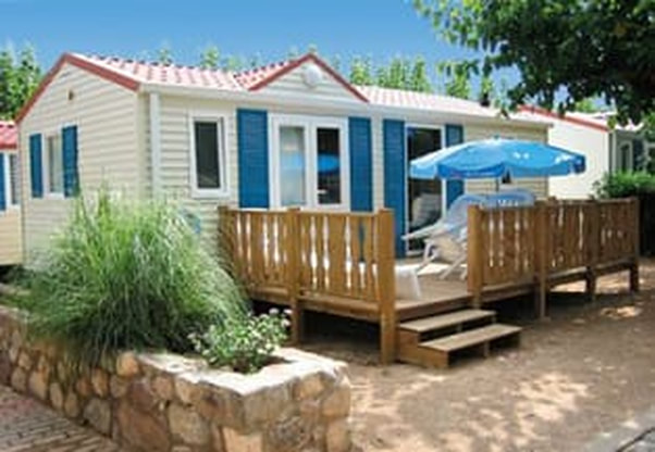 Picture of a white mobile home with blue shutters and a wooden front deck.